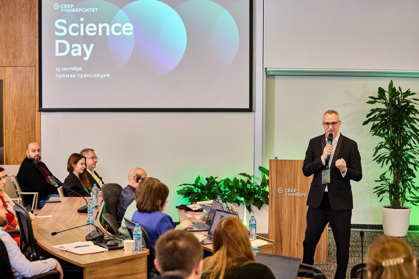 Павел Ершов с микрофоном у трибуны «Сбер Университета», на экране заставка Science Day